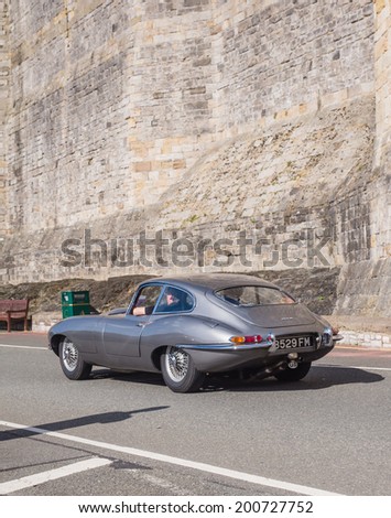 CAERNARFON, WALES - 29 SEPTEMBER 2013: Vintage classic Jaguar car taking part in the Walled Towns Trail Car Run 2013 passes the walls of Caernarfon Castle en route to its next destination
