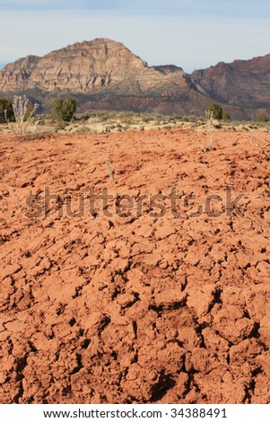 Dry, cracked earth in the northern Arizona desert with cliffs in background. Arizona Strip, USA.