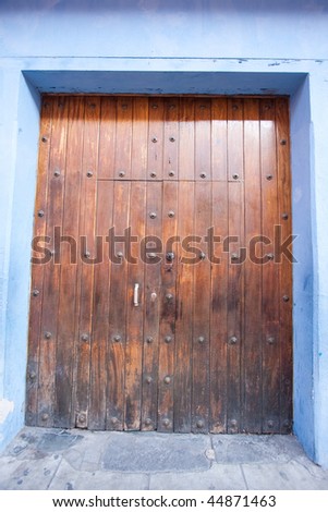 Wooden door framed by blue colored walls in Antigua, Guatemala.