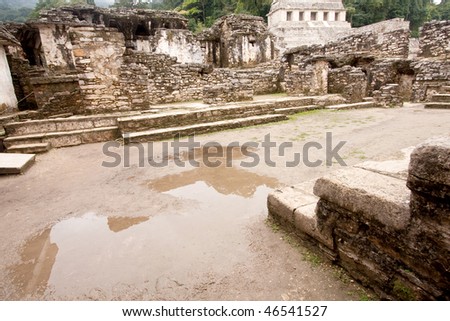 Wide angle view inside \'The Palace\' with pyramid and steamy jungle in background at the ancient Mayan city of Palenque. Chiapas, Mexico.