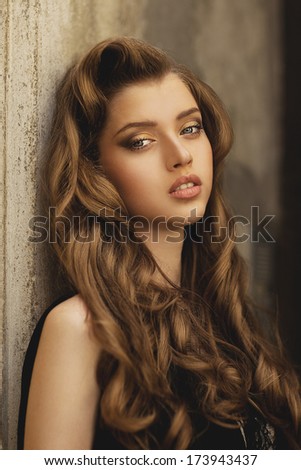 Portrait of elegant woman with curly hairstyle in black dress  Elegant woman. Portrait of beautiful woman. High fashion model. Fashion hairstyle. Hollywood style.