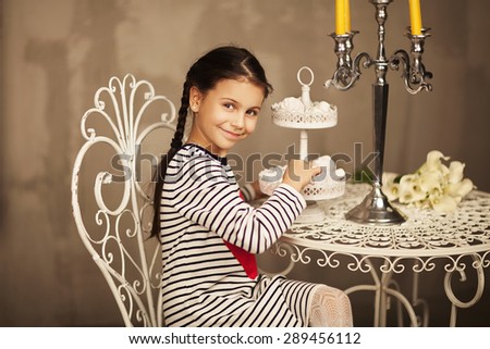 Beautiful Little girl sitting and going to eat cakes. Beautiful little girl. Smiling kid. Window with lights. Warm planket.