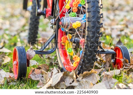 closeup look of wheels full of ornaments of young child\'s bike with accessory wheels