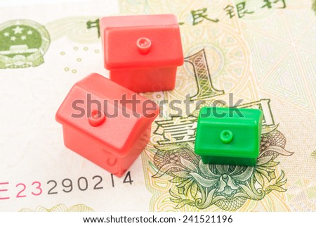 Three little houses made of plastic are laying on one yuan banknote