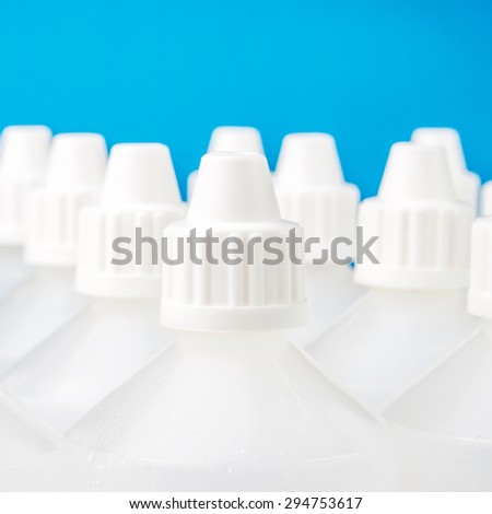 white translucent bottles forming rows and used in homeopathy with one specific focused bottle on blue and blurred bottles background