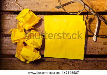 yellow blank paper with crumpled paper with glasses on wood pettern background