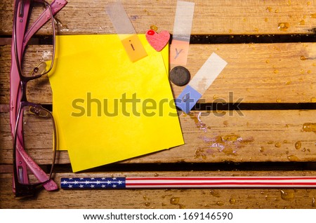 yellow blank paper with i love you alphabet with pink glasses and pencil  on wood pettern background