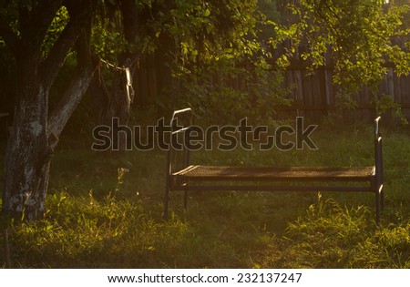 Empty iron bed in the garden in the evening sun