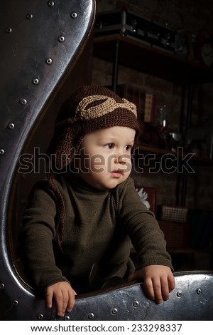 Cute toddler wearing aviator hat in egg chair