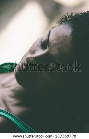 Tender portrait of a beautiful young woman resting with her eyes closed in a shadowed room, closeup of her face