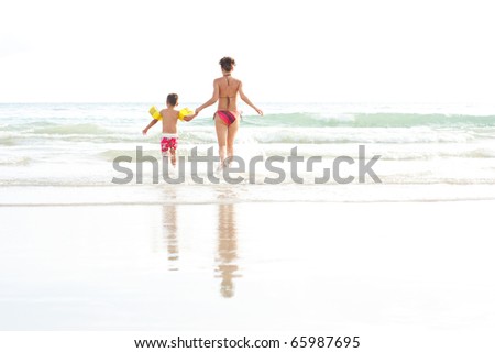 Young mother and her son running into water