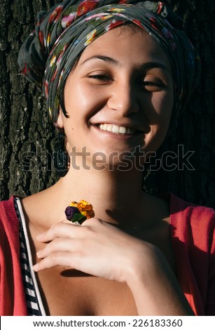 Close up Happy Young Woman with Head Cover and Floral Ring Leaning on Tree.