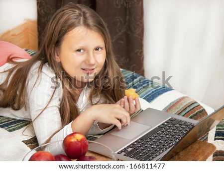 Caucasian child (girl) using laptop on the bed with smile