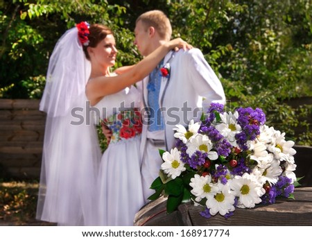 Ukraine. Happy ukranian wedding (bridal) couple in the ukrainian style.  Beautiful bride and groom in the ukrainian style are standing with bouquet. Female and male models. Outdoors, close up.