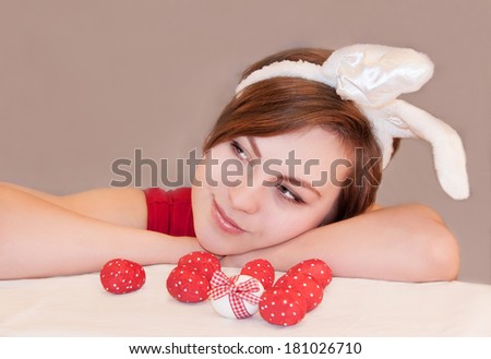 Portrait of a young  woman wearing easter bunny ears. Easter eggs near her. Indoor.