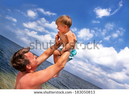 Portrait of caucasian happy son and father at the beach on the sky background. Relaxing family. Summer vacations concept. Outdoor. Close up.