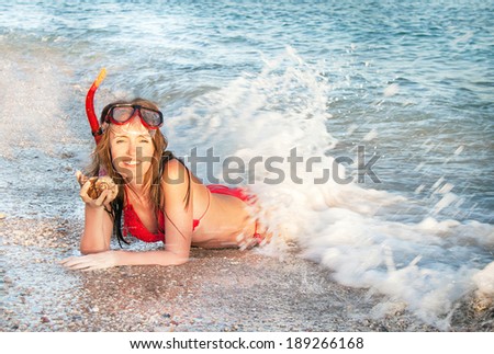 Caucasian girl lying and relaxing on the summer beach with snorkeling mask and fins. Happy woman is smiling  with shellfish (muscle-fish) in sunny summer day (Sharm El Sheikh, Egypt).