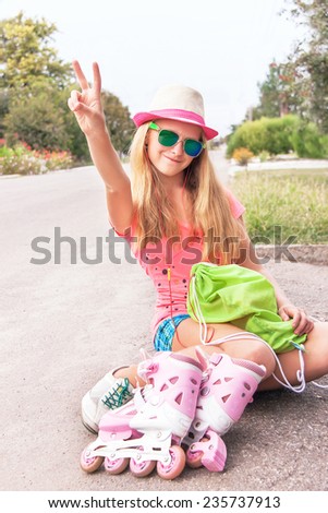Teenager (girl) sitting with roller skating shoes (inline skates), listening music with headphone. Teen wearing sunglasses, showing victory v hand sign, having fun. Concept of youth, sport, lifestyle.