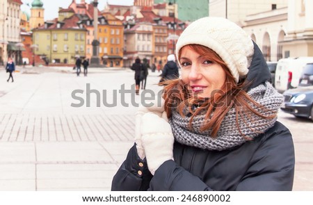 Portrait of trendy hipster girl in winter clothes. Caucasian female model wearing coat, hat, mittens. Woman having fun in the capital city of Poland - Warsaw. Travel, winter, lifestyle concept.