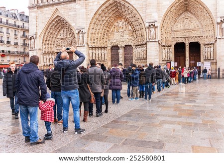 Paris, France - January 9, 2015:  Long queue (crowd) of people waiting in line to Notre Dame de Paris. People queueing in front of entrance.  Notre Dame is one of the most popular destinations.