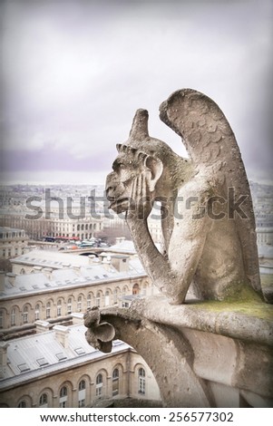 Gargoyle (chimera), famous stone demons, with Paris city on background. View from the tower of the Notre Dame de Paris cathedral. France. Travel, architecture concept. Copy space. Place for text.