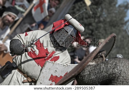 Knight in full helmet with shield fights against his opponent on festival of medieval culture.