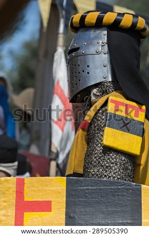 Knight in iron helmet with wooden shield from medieval century prepares to fight against his opponent on festival of ancient culture.