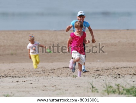 group of three child  who have fun and run on the beach