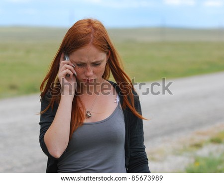 one red-haired young girl outdoor about road to speak on the mobil phone