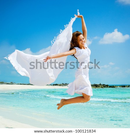 Beautiful Girl With White Scarf Jumping on The Beach. Travel and Vacation. Freedom Concept