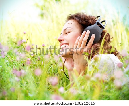 Beautiful Young Woman With Headphones Outdoors. Enjoying Music