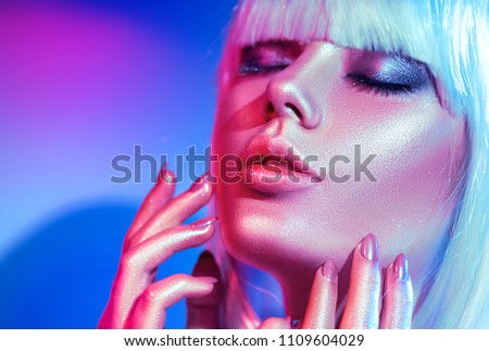 High Fashion model woman in colorful bright sparkles and neon lights posing in studio, portrait of beautiful girl, trendy glowing make-up. White hair, colorful make up. Glitter Vivid neon makeup