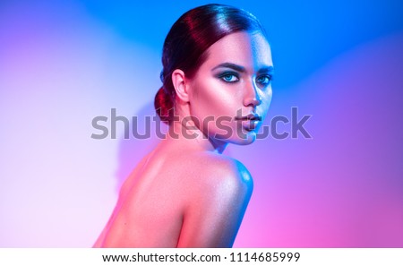 High Fashion model girl in colorful bright sparkles and neon lights posing in studio, portrait of beautiful woman, trendy glowing make-up. Art design colorful make up. Glitter Vivid neon makeup