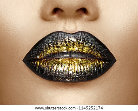 Lips make-up. Beauty high fashion trendy black with gold colour gradient lips makeup sample, sexy mouth closeup. Lipstick. Professional Make up artist work
