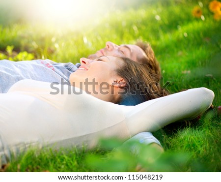 Happy Smiling Couple Relaxing on Green Grass.Park.Young Couple Lying on Grass Outdoor