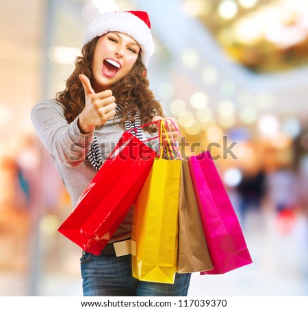 Christmas Shopping. Fashion Girl With Shopping Bags in Shopping Mall showing Thumb up