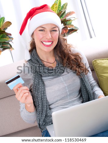 Christmas Online Shopping. Happy Smiling Woman Using Credit Card to Internet Shop. Young Girl with laptop and credit card buying online. Christmas and New Year Gifts. e-shopping