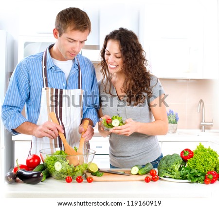 Cooking.Happy Couple Cooking Together - Man and Woman in their Kitchen at home Preparing Vegetable Salad.Diet.Dieting. Healthy Food Tasting
