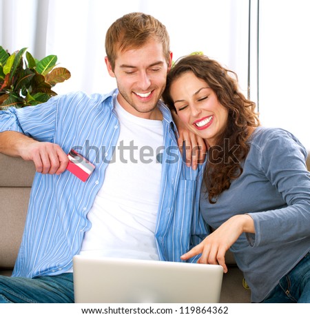 Family Shopping Online .Happy Smiling Couple Using Credit Card to Internet Shop on-line. Couple with Laptop Computer and Credit Card buying on-line. Christmas and New Year Gifts. e-shopping.ecommerce