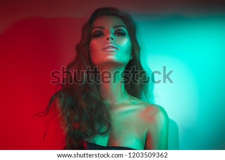 High Fashion model woman in colorful bright lights posing in studio, night club. Portrait of beautiful sexy girl with trendy make-up. Neon Art design, colorful make up. On colourful vivid background