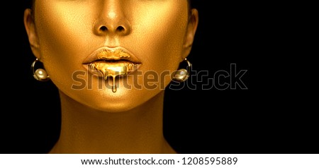 Gold Paint drips from the lips, lipgloss dripping from sexy lips, golden liquid drops on beautiful model girl\'s mouth, gold metallic skin make-up. Beauty woman face makeup close up, isolated on black