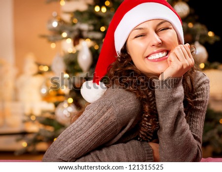 Christmas Woman in Santa Hat.Happy Smiling Girl Celebrating New Year at Home. Christmas Tree