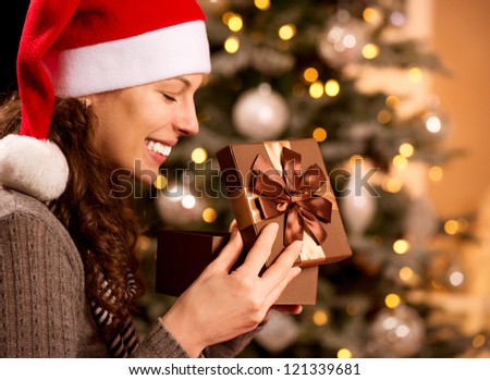 Christmas Gift.Happy Surprised Woman opening Gift box at home. Christmas Tree