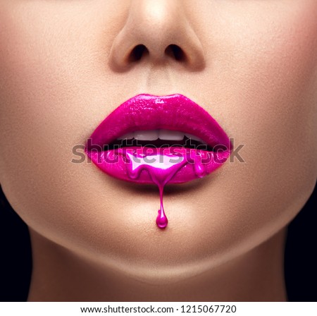 Pink Lipstick dripping. Paint drips from the lips, lipgloss dripping from sexy lips, Purple liquid drops on beautiful model girl\'s mouth, creative abstract make-up. Beauty woman face makeup close up