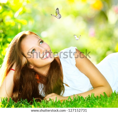 Spring Beauty Girl. Beautiful Young Woman Lying On Green Grass Outdoor. Park. Meadow. Summer. Spring Girl Lying On The Field. Happiness. Outdoors. Youth Concept