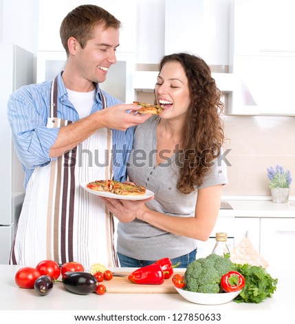 Happy Couple Eating Pizza Cooking Together Homemade Pizza Smiling Family in the kitchen Preparing And Tasting Food Happy Couple Eating Pizza Cooking Together Homemade Pizza Smiling Family in the kitchen Preparing And Tasting Food