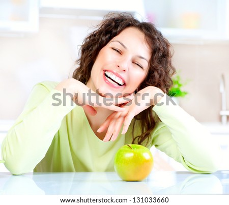 Happy Young Woman Eating Apple on Kitchen. Diet. Dieting concept. Healthy food. Loosing Weight