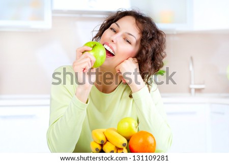 Happy Young Woman Eating Apple on Kitchen. Diet. Dieting concept. Healthy food