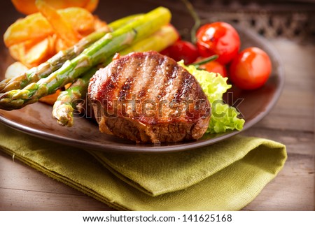Steak Dinner. Grilled Beef Steak Meat with Fried Potato, Asparagus and Cherry Tomato. Food