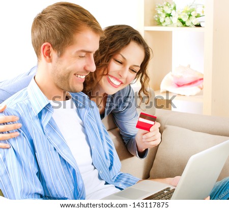 Internet Online Shopping. Happy Smiling Couple Using Credit Card to Internet Shop. Young couple with laptop and credit card buying online. E-shopping. Paying Online